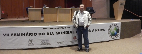 Pesquisador em frente ao púlpito do Seminário, com faixa do evento atrás