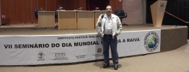 Pesquisador em frente ao púlpito do Seminário, com faixa do evento atrás