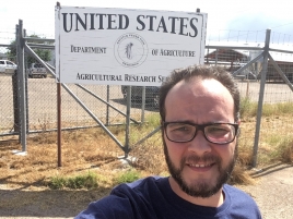 Autorretrato do pesquisador em frente a uma placa que diz United States, Department of Agriculture